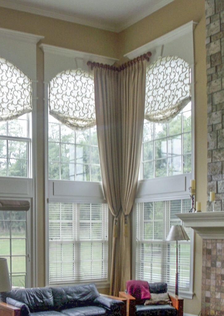 Arched window with layered faux Roman valance, drapery panels, and functional blinds