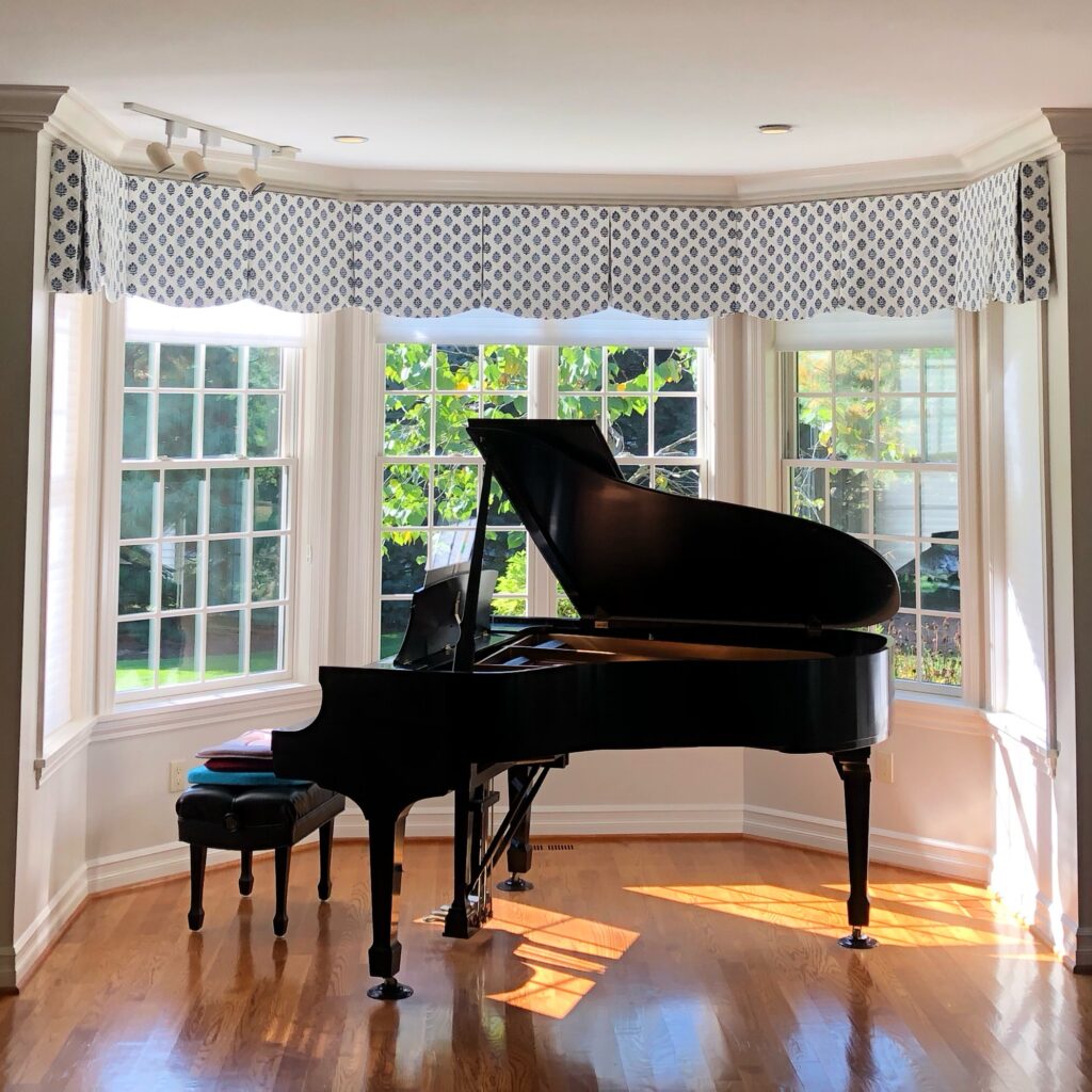 Bay window with custom valances framing elegant piano room architecture